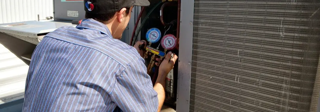 HVAC technician servicing a condenser unit in Tualatin